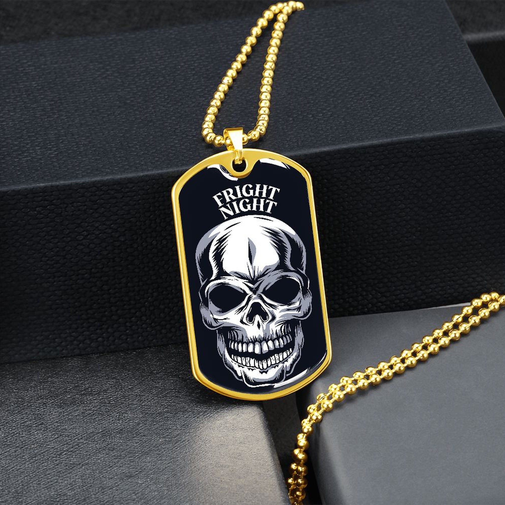 Gold-finish Fright Night skull dog tag hanging over a black gift box