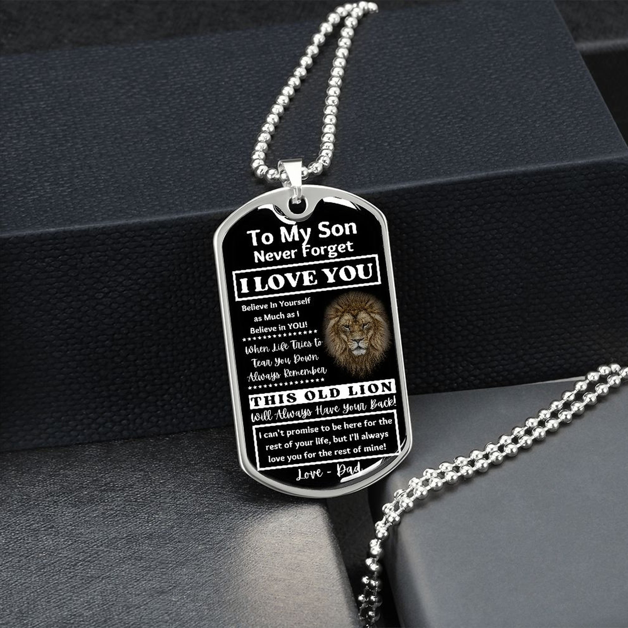 Silver Old Lion son dog tag hanging over a black gift box