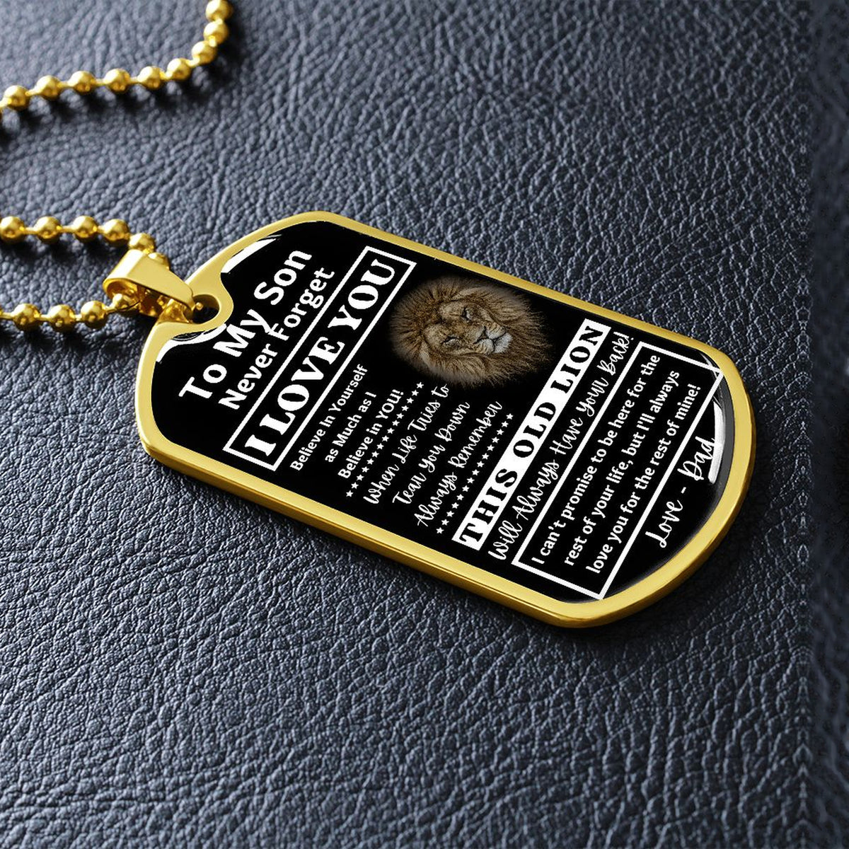Gold-finish Old Lion son dog tag lying on black leather