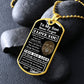 Gold-finish Old Lion son dog tag propped on dark river rocks