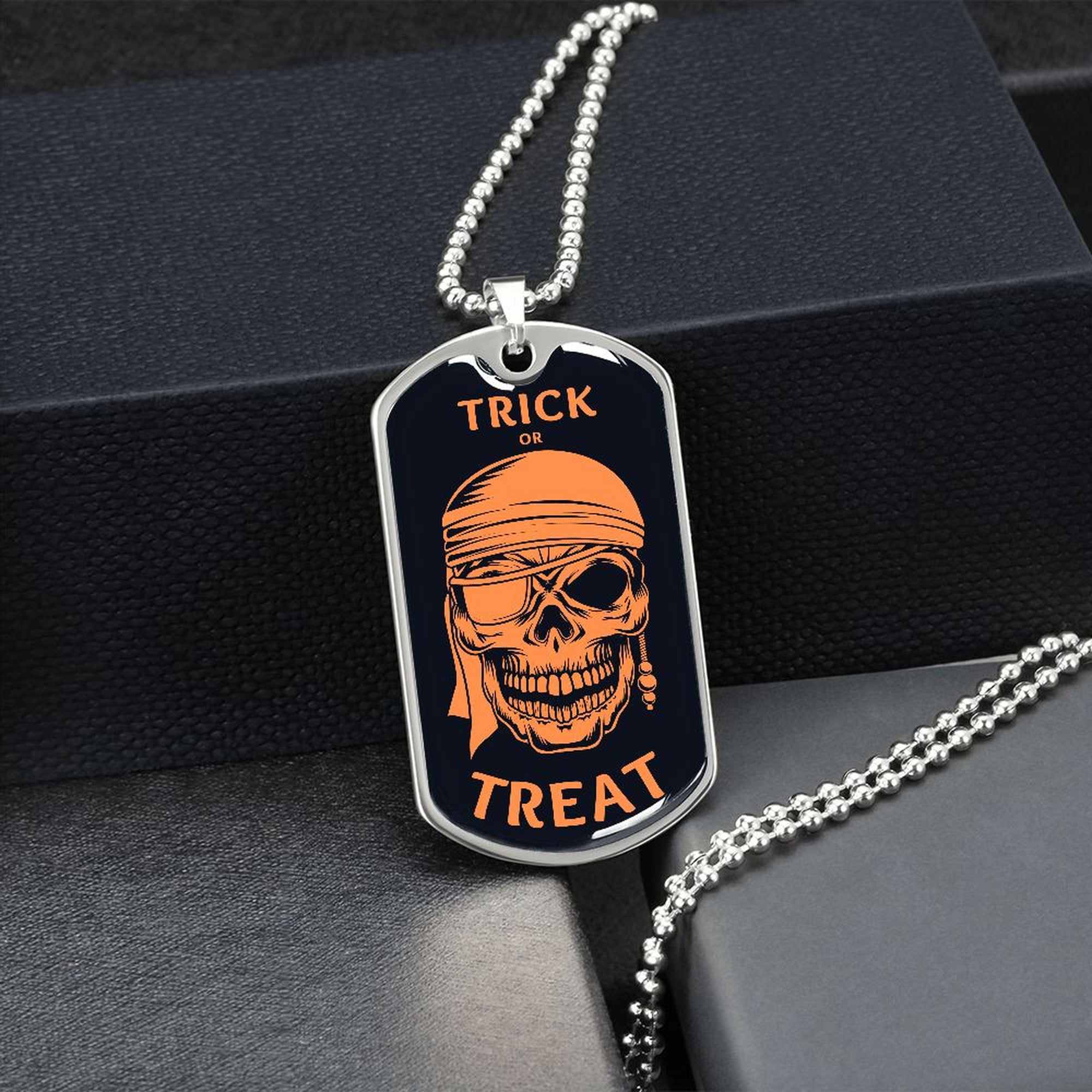 Silver Trick or Treat pirate skull dog tag hanging over a black gift box