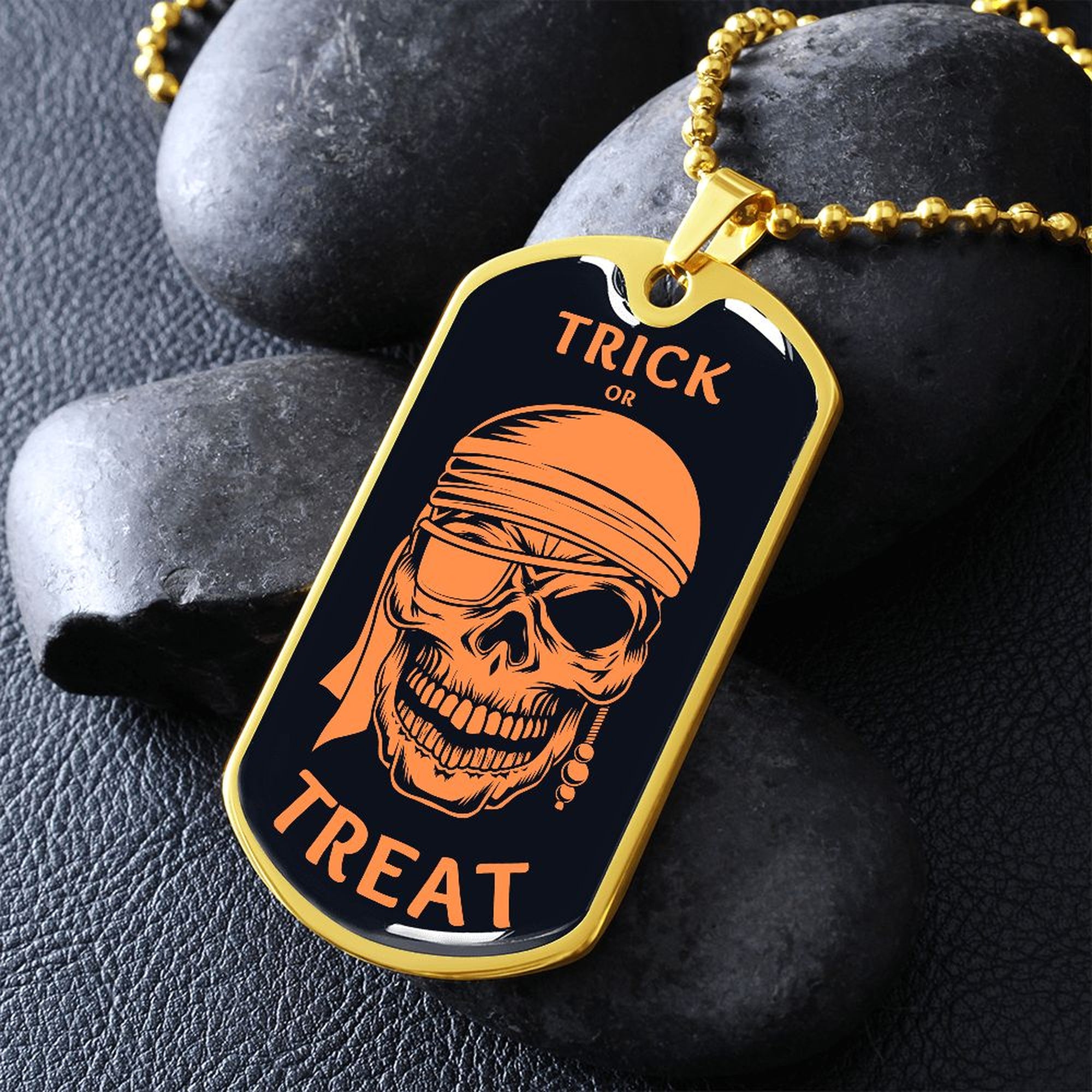 Gold-finish Trick or Treat pirate skull dog tag necklace propped on dark river rocks