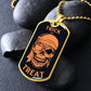 Gold-finish Trick or Treat pirate skull dog tag necklace propped on dark river rocks