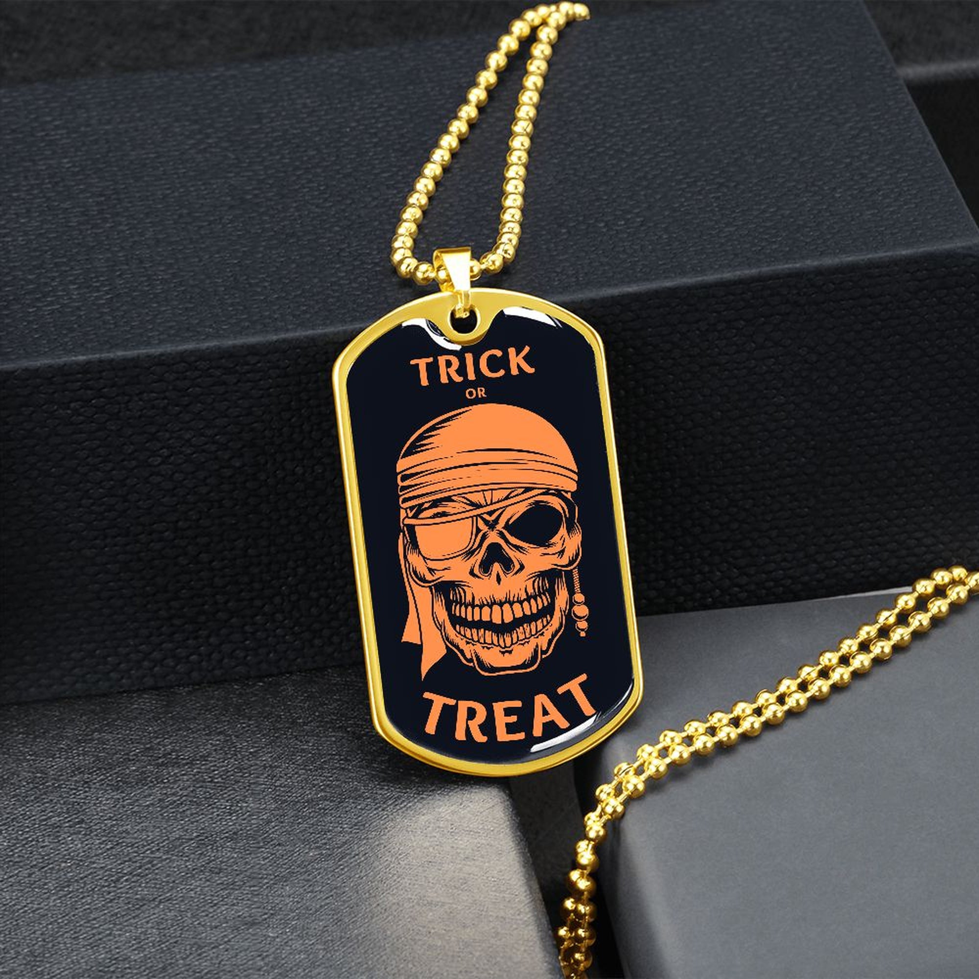 Gold-finish Trick or Treat pirate skull dog tag hanging over a black gift box