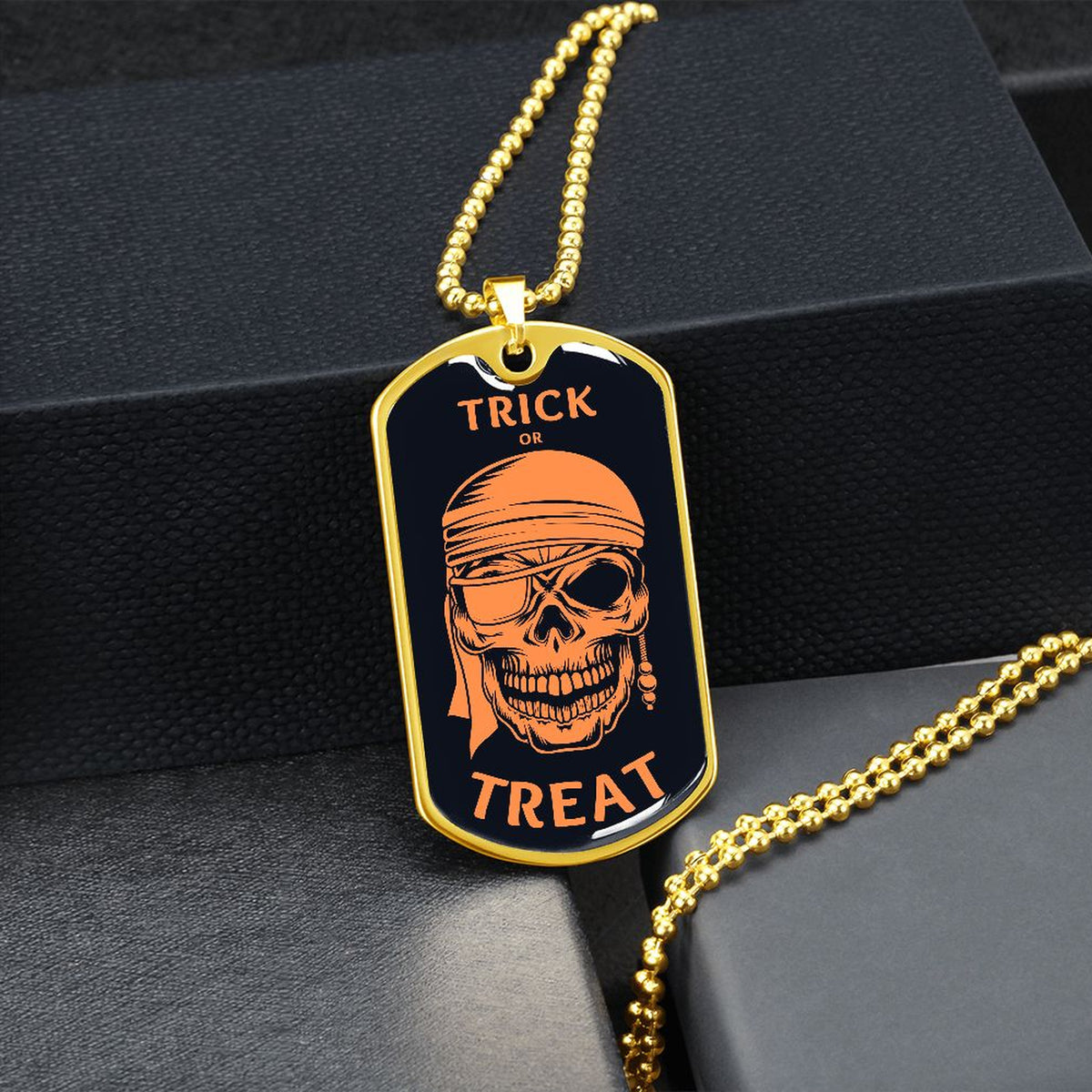 Gold-finish Trick or Treat pirate skull dog tag hanging over a black gift box