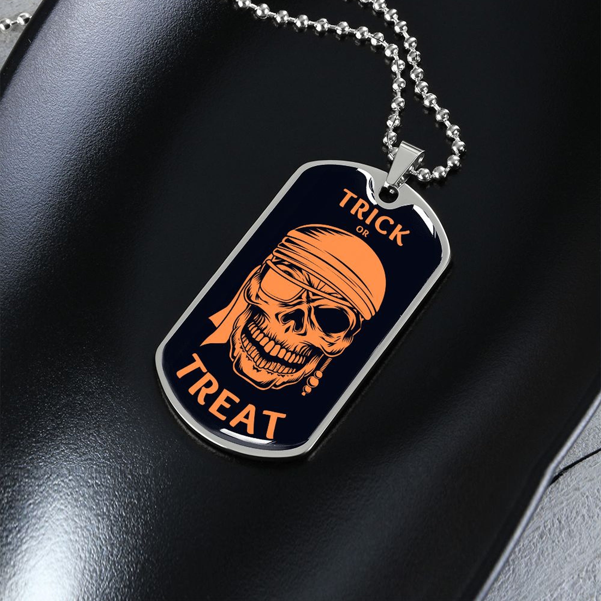 Silver Trick or Treat dog tag necklace on a dark dish