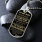 Silver To My Son dog tag propped on dark river rocks