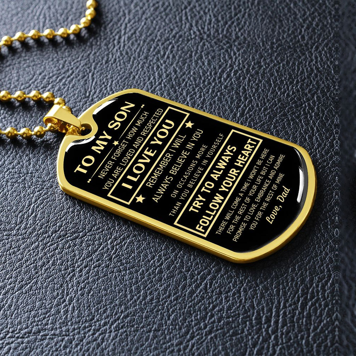 Gold-finish To My Son dog tag lying on black leather