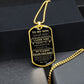 Gold-finish To My Son dog tag propped on dark river rocks